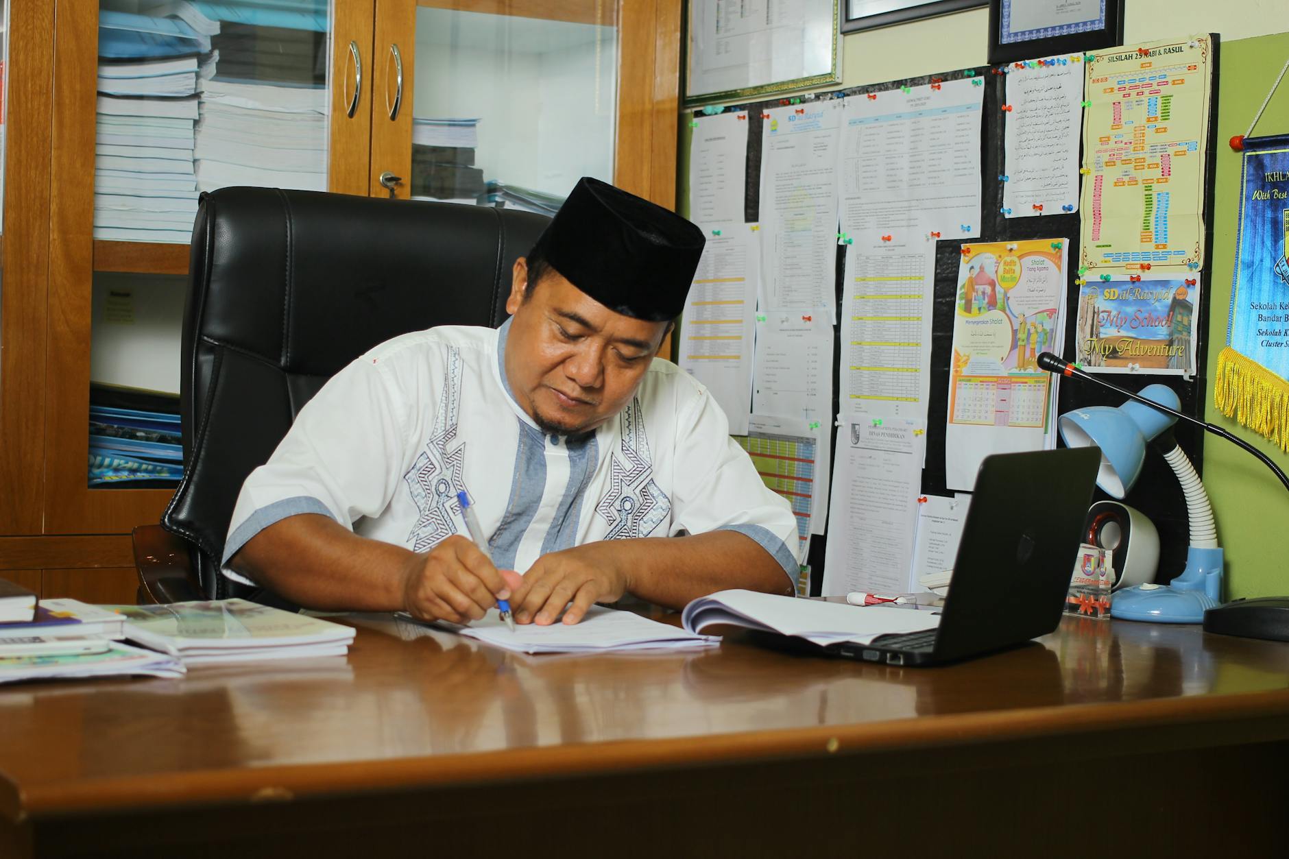 A digital illustration of Cikgu Suraya, a teacher, standing in a bright classroom setting.